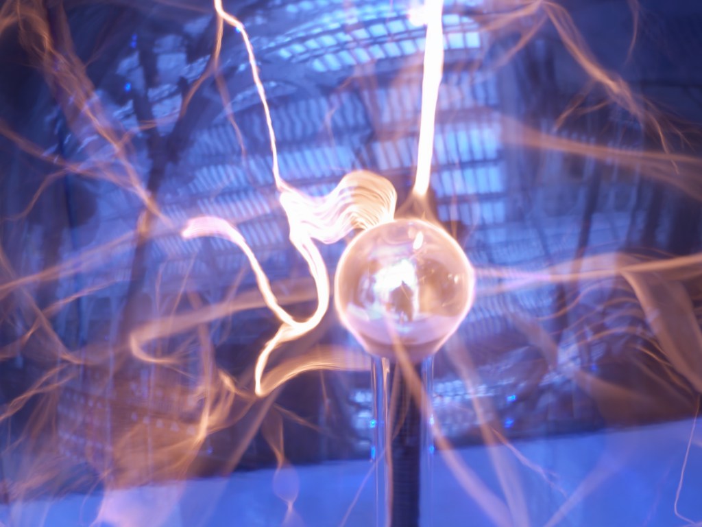 An abstract image of a plasma globe with electric arcs and glowing light against a blue background, showcasing the dynamic movement of electricity.