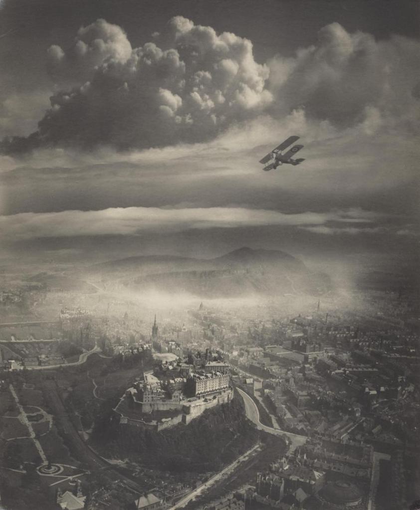 Aerial view of a historic cityscape featuring a castle on a hill, with an old biplane flying in the sky and dramatic clouds overhead.